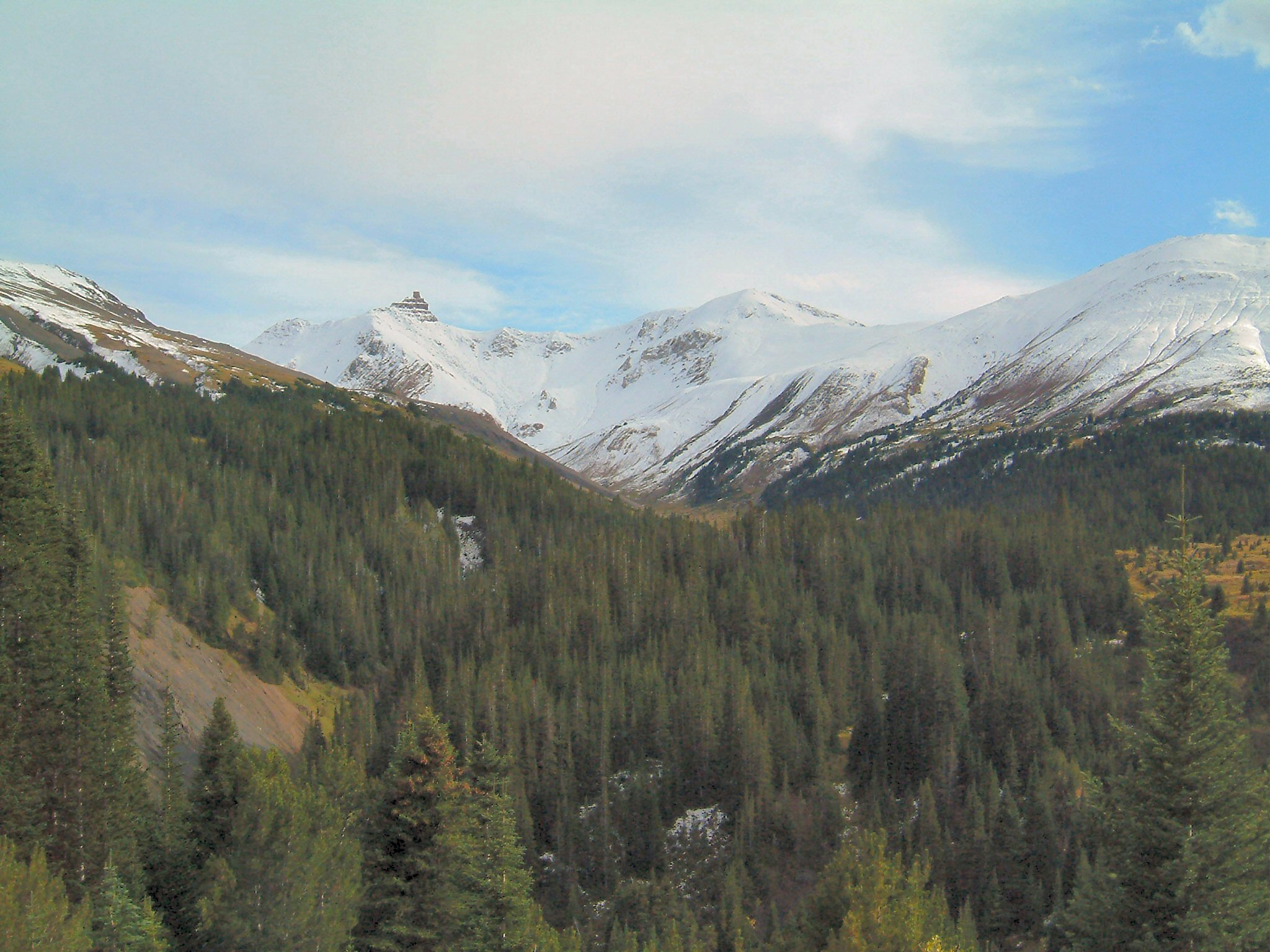 View on snow covered sandy shale mountain tops with forested valleys.